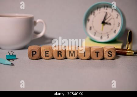 permis - mot de blocs de bois avec des lettres sur fond gris. Réflexion de la légende sur la surface symétrique de la table. Mise au point sélective. Banque D'Images