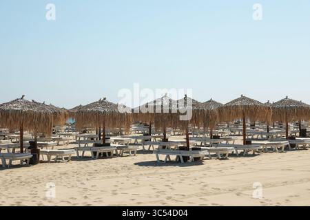 Superbes parasols en paille et transats sur une plage de sable Banque D'Images