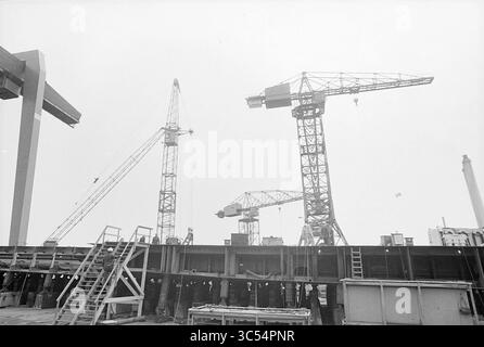 Visite guidée N.D.S.M., Amsterdam, visite guidée et visite, 07-06-1978 Whizgle News, Dutch Desk, pays-Bas, 1950-2000 Un chantier de construction animé avec plusieurs grandes grues surplombant une structure partiellement construite, avec des échafaudages et des équipements dispersés dans toute la région. La scène capture l'atmosphère industrielle du bâtiment actif et des travaux d'ingénierie. Banque D'Images