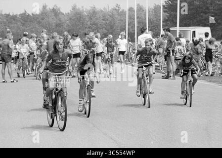 Mosquito Round, Mosquito Round, 28-07-1980','29-07-1980','31-07-1980','01-08-1980','02-08-1980 Whizgle News, Dutch Desk, pays-Bas, 1950-2000 Une scène animée représentant un groupe d'enfants à vélo sur un chemin lisse, certains se concentrant sur la course tandis que d'autres apprécient une promenade tranquille. En arrière-plan, de nombreux spectateurs sont rassemblés, contribuant ainsi à l’atmosphère vibrante d’un événement communautaire. Banque D'Images
