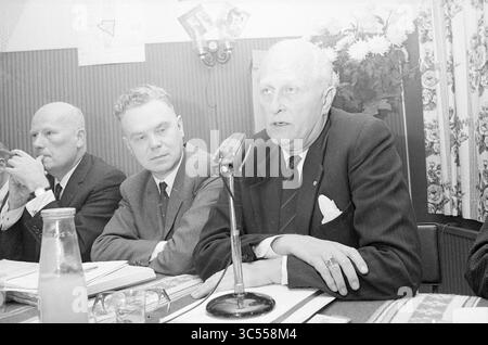 Teach-In Noise pollution Schiphol, Schiphol, 02-11-1967 Whizgle News, Dutch Desk, pays-Bas, 1950-2000 Un groupe de trois hommes est assis à une table pendant une réunion, un homme parlant dans un microphone. Les individus semblent engagés dans la discussion, et il y a des documents et une bouteille devant eux, avec une toile de fond de rideaux à motifs floraux. Banque D'Images