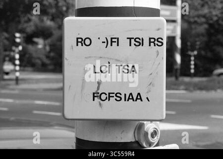 Panneau pour cyclistes Heemsteedse Dreef, Borden, Heemstede, Heemsteedse Dreef, pays-Bas, 22-08-1989 Whizgle News, Dutch Desk, pays-Bas, 1950-2000 Une boîte utilitaire dans une rue de la ville, affichant un assortiment de lettres et de symboles disposés de manière apparemment mélangée. La zone environnante fait allusion à un environnement urbain animé avec des infrastructures de circulation visibles en arrière-plan. Banque D'Images