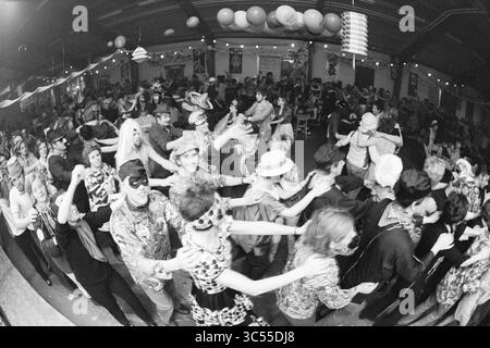 Carnaval à Noordwijkerhout, Carnaval, 22-02-1971 Whizgle News, Dutch Desk, pays-Bas, 1950-2000 Une foule animée remplit un lieu animé, dansant dans une ligne ludique avec des costumes et des accessoires festifs. Des décorations colorées pendent du plafond, tandis que les invités portant des chapeaux, des lunettes et des vêtements ludiques profitent de l'atmosphère énergique, célébrant ensemble dans un joyeux rassemblement. Banque D'Images