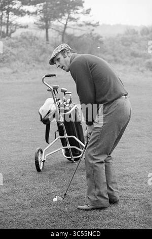 Barry Hughes on golf course, Golf, Golf, Football People and trainers, 13-11-1975 Whizgle News, Dutch Desk, pays-Bas, 1950-2000 Un golfeur se prépare à prendre un coup de feu, concentré intensément alors qu'il se tient près d'un sac de golf sur une voiturette. Il porte une casquette plate et un pull confortable, soulignant une scène de golf classique sur un parcours verdoyant. Banque D'Images