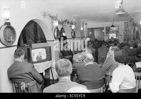 Teach-In Noise pollution Schiphol, Schiphol, 02-11-1967 Whizgle News, Dutch Desk, pays-Bas, 1950-2000 Un groupe de personnes est assis tranquillement dans une pièce confortable, engagé avec une télévision diffusant un segment d'information. Ils regardent attentivement, certains individus prenant des notes, tandis que l'ambiance est rehaussée par un décor vintage et un éclairage chaleureux. Banque D'Images