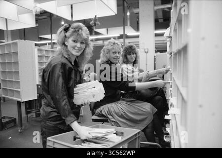 Trier code postal PTT Haarlem, PTT, services postaux, ville poste, Haarlem, pays-Bas, 22-12-1988 Whizgle News, Dutch Desk, pays-Bas, 1950-2000 trois femmes organisent et trient des dossiers dans un environnement de bureau très fréquenté. Ils sont souriants et semblent concentrés sur leurs tâches, entourés d'étagères et de piles de documents. Banque D'Images