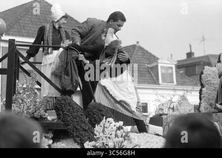 Flower Parade Haarlem, Flower Parade, exposition de fleurs, Haarlem, pays-Bas, 25-04-1987 Whizgle News, Dutch Desk, pays-Bas, 1950-2000 Un moment joyeux lors d'une célébration festive, mettant en vedette un homme s'engageant de manière ludique avec deux femmes vêtues de vêtements traditionnels, entourées de décorations florales vibrantes. La scène capture l'esprit de communauté et de fête, mettant en valeur les traditions culturelles. Banque D'Images