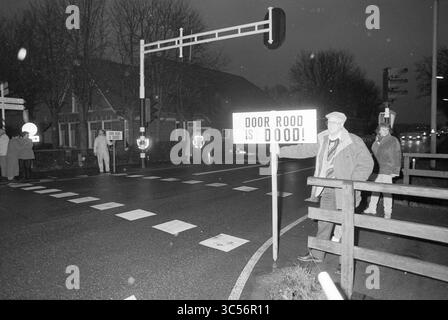 Intersection Schipholweg, Hoofdweg, Haarlem, Schipholweg, pays-Bas, 06-01-1991 Whizgle News, Dutch Desk, pays-Bas, 1950-2000 Un groupe d'individus se tient dans une rue, avec une personne tenant une pancarte qui dit : « DOOR ROOD IS DOOD ! » feux de circulation à proximité et un portail de passage à niveau, comme il semble être le soir ou la nuit. Banque D'Images