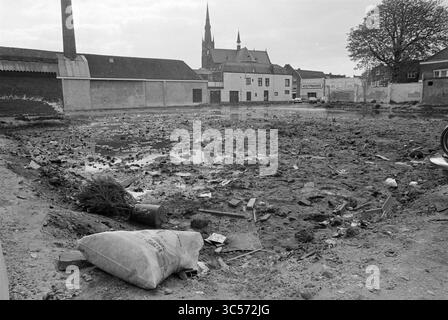 Terrain Raamsteeg, terrains, Haarlem, Raamsteeg, Nederland, 17-04-1981 Whizgle News, Dutch Desk, pays-Bas, 1950-2000 Un paysage urbain désolant, rempli de boue et de débris, présente les vestiges d'un site démoli. Des matériaux de construction éparpillés et des déchets entourent une flaque d'eau, tandis que la silhouette d'un clocher d'église s'élève en arrière-plan, évoquant une communauté autrefois dynamique. Banque D'Images