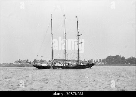 Goélette, IJmuiden, navires, 17-07-1972 Whizgle News, Dutch Desk, pays-Bas, 1950-2000 Un voilier classique avec trois grands mâts glisse gracieusement sur des eaux calmes, entouré d'un rivage orné d'arbres et de bâtiments lointains. Banque D'Images