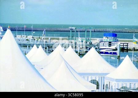 HISWA te Water, IJm., IJmuiden, pays-Bas, 04-09-1995 Whizgle News, Dutch Desk, pays-Bas, 1950-2000 Une scène côtière sereine avec d'élégantes tentes blanches bordant le front de mer, avec un quai et des bateaux en arrière-plan, face à un océan tranquille. Banque D'Images