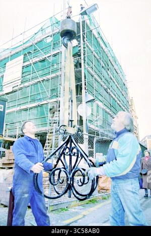 Lors de la restauration du Hoofdwacht, une girouette portant le logo de l’Association Haerlem sera placée sur une cheminée. La girouette a été faite par le forgeron ornemental AB Vermeulen (à droite sur la photo) qui a aidé à l'installation. Grote Markt corner of Smedestraat, Haarlem., Haarlem, Grote Markt, pays-Bas, 02-11-1994 Whizgle News, Dutch Desk, pays-Bas, 1950-2000 deux travailleurs utilisent un système de poulie pour soulever une pièce ornée de métal vers un chantier de construction entouré d'échafaudages. Un travailleur se concentre sur le guidage du métal, tandis que l'autre lo Banque D'Images
