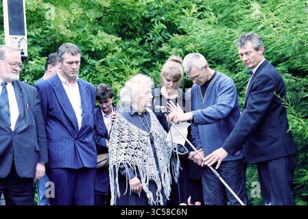 Funérailles Frans Verpoorten, Zwanenburg, Zwanenburg, 01-07-1997 Whizgle News, Dutch Desk, pays-Bas, 1950-2000 Un groupe d'individus se réunit dans un cadre extérieur luxuriant, avec un mélange d'expressions solennelles et d'attention concentrée. Une femme âgée, drapée dans un châle tricoté, se tient au centre, entourée de plusieurs hommes et femmes, certains tenant un long bâton. L'atmosphère suggère un moment important, peut-être une cérémonie ou un hommage, alors que les participants s'engagent les uns avec les autres dans un cadre de verdure vibrante. Banque D'Images