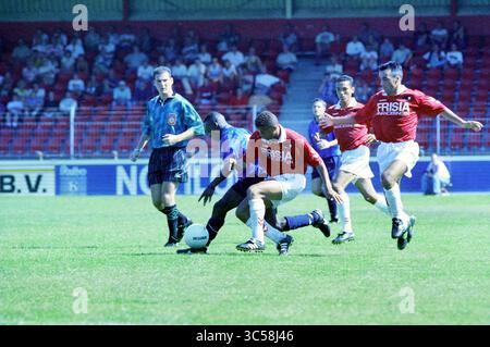AZ - Telstar, 19-08-1995 Whizgle News, Dutch Desk, pays-Bas, 1950-2000 Un groupe de joueurs de football est engagé dans un match intense, avec un joueur qui dribble habilement le ballon tandis que d'autres poursuivent dans une démonstration dynamique de travail d'équipe et d'athlétisme. La scène capture l'excitation et l'esprit de compétition du jeu, avec des spectateurs en arrière-plan qui encouragent leurs équipes. Banque D'Images