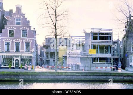 Cour du 21e siècle, Haarlem, Spaarne, pays-Bas, 29-02-2000 Whizgle News, Dutch Desk, pays-Bas, 1950-2000 Une vue sur le canal avec un mélange d'architecture historique et un chantier de construction moderne, avec des échafaudages et des matériaux de construction au premier plan, contrastant avec les bâtiments traditionnels de l'autre côté de l'eau. Banque D'Images