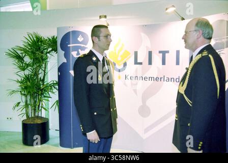 Officiers assermentés, Haarlem, pays-Bas, 26-02-2001 Whizgle News, Dutch Desk, pays-Bas, 1950-2000 deux individus en tenue de cérémonie engagent une conversation près d'un fond arborant un logo lié à l'application de la loi, avec une petite plante en pot à proximité. Banque D'Images