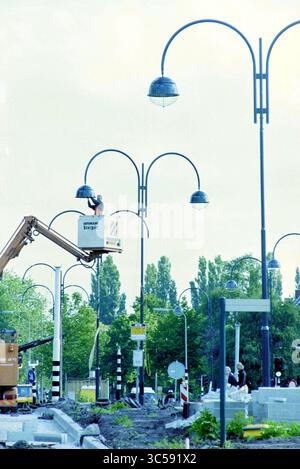 Lampadaires sur le Heemsteedse Dreef à Heemstede, Heemstede, Heemsteedse Dreef, pays-Bas, 16-06-1997 Whizgle News, Dutch Desk, pays-Bas, 1950-2000 Une équipe de construction travaille à l'installation de lampadaires le long d'une chaussée très fréquentée, avec des panneaux de signalisation et des arbres bordant la zone. Un ascenseur est positionné sous l'un des hauts lampadaires, où un travailleur est engagé dans le processus d'installation. Banque D'Images
