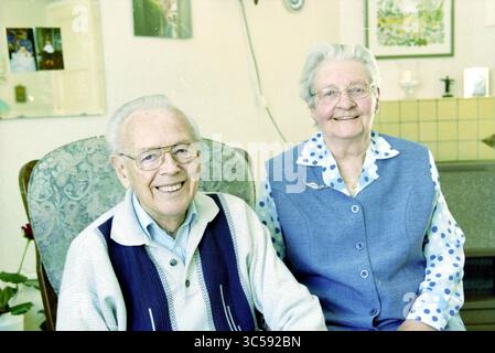 Family de Zwart, Haarlem, pays-Bas, 05-05-2002 Whizgle News, Dutch Desk, pays-Bas, 1950-2000 Un couple de personnes âgées joyeux s'assoit ensemble, souriant chaleureusement. L'homme porte un pull confortable et des lunettes, tandis que la femme est habillée d'une tenue bleu clair avec une chemise à pois, rayonnant de joie dans leur espace confortable et accueillant. Banque D'Images