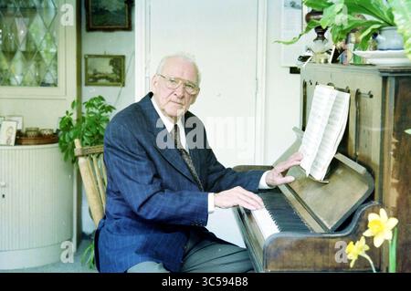 Mr. Tange@Man, Haarlem [Tangerman], Haarlem, pays-Bas, 24-02-1999 Whizgle News, Dutch Desk, pays-Bas, 1950-2000 un homme âgé en costume est assis devant un vieux piano, jouant attentivement de la musique à partir d'une feuille sur le stand. Autour de lui se trouvent des plantes en pot et un décor qui suggèrent un espace confortable et habité. Son expression reflète un mélange de concentration et de joie. Banque D'Images