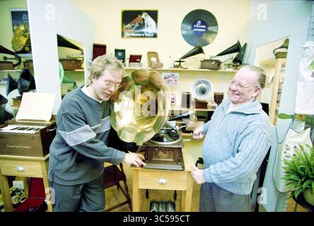 Gramophone Shop Haarlem, Haarlem, Spaarnwouderstraat, pays-Bas, 17-01-2001 Whizgle News, Dutch Desk, pays-Bas, 1950-2000 deux hommes interagissent joyeusement avec un gramophone vintage dans une boutique confortable remplie de divers instruments de musique anciens. Un homme fait fonctionner le gramophone tandis que l'autre regarde avec enthousiasme, les deux partageant un moment de nostalgie parmi les objets uniques qui les entourent. Banque D'Images