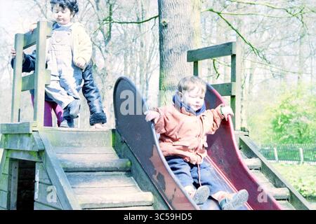 Immigrant Kid's, Farm, Haarlem, pays-Bas, 15-04-2000 Whizgle News, Dutch Desk, pays-Bas, 1950-2000 deux enfants aiment jouer sur un toboggan dans une aire de jeux, avec un enfant glissant joyeusement vers le bas tandis qu'un autre se prépare à monter. Les arbres luxuriants offrent une toile de fond naturelle, créant une scène de plein air animée. Banque D'Images