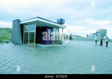 ATM Rabo, Kennemerboulevard, IJmuiden, IJmuiden, Kennemerboulevard, pays-Bas, 30-04-2003 Whizgle News, Dutch Desk, pays-Bas, 1950-2000 Un kiosque moderne au design épuré avec de grandes fenêtres et un extérieur bleu et violet distinctif, situé le long d'une passerelle pavée. En arrière-plan, quelques personnes se promènent, avec un espace ouvert et un soupçon d'environnement de plage visible. Banque D'Images