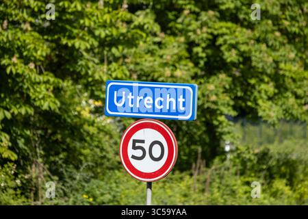 Un panneau d'entrée clair « Utrecht » et un panneau de limitation de vitesse de 50 km/h, bien en vue sur un fond vert vif et ensoleillé. Banque D'Images