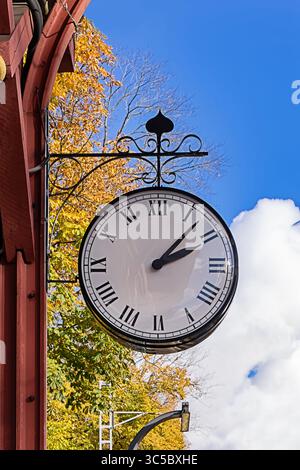 Street clock in autumn colors reminds of symbolizing seasonal transition in Europe. Clock with classic roman design and vintage street style Banque D'Images