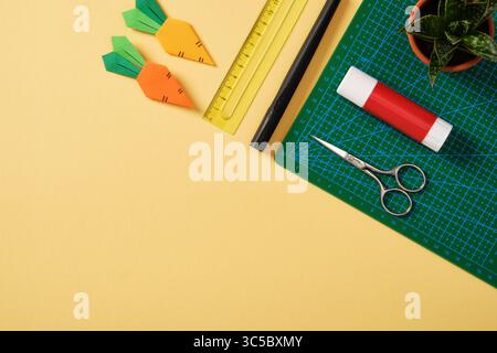 Fournitures pour le passe-temps de l'art du papier : ciseaux, couteau artisanal, crayon, gomme, papier coloré. Espace pour votre texte. Papier artisanat table de travail plat. Banque D'Images