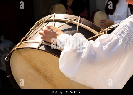 Musicien dans une chemise blanche traditionnelle jouant une grande grosse grosse grosse grosse grosse caisse folklorique. Banque D'Images