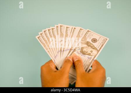 Des billets de cent dollars AMÉRICAINS sont tenus dans une main, prêts à être donnés. Banque D'Images