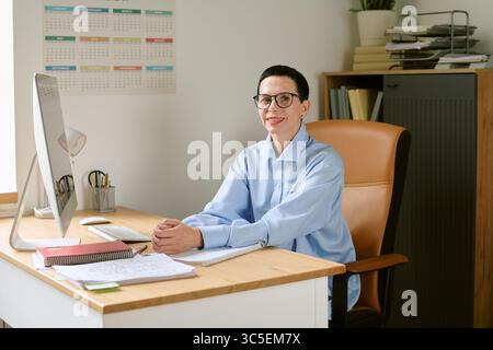 Portrait de femme caucasienne d'âge moyen assise au bureau souriant avec confiance Banque D'Images