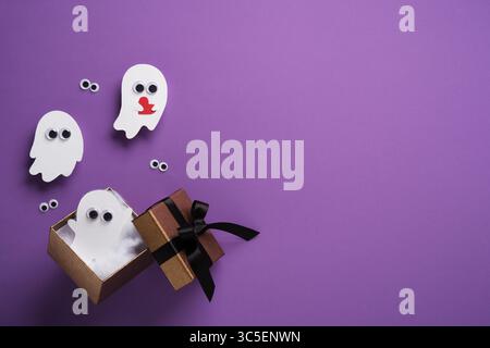 Mignon papier fantômes d'Halloween avec coeur volant hors d'une boîte cadeau sur fond violet. Fond pour les cartes d'Halloween, les bannières, les invitations. Place pour Banque D'Images