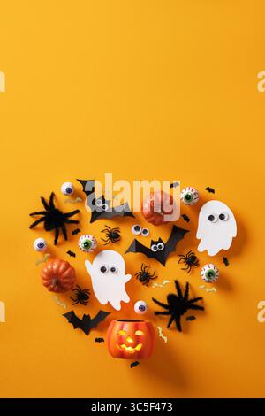 Bannière verticale en forme de cœur d'Halloween avec des coeurs hantés, des chauves-souris, des citrouilles, des araignées, des globes oculaires et un squelette sur fond jaune. Espace pour votre texte, Banque D'Images