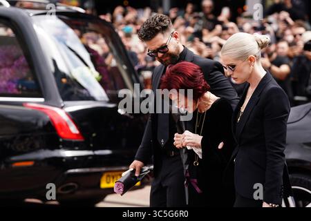 La famille d'Ozzy Osbourne (de gauche à droite) Jack Osbourne, Sharon Osbourne et Kelly Osbourne déposent des fleurs et regardent les messages et hommages floraux laissés sur le banc du pont Black Sabbath sur Broad Street à Birmingham en mémoire du chanteur Black Sabbath Ozzy Osbourne, alors que son corps est ramené dans sa ville natale pour une procession après sa mort la semaine dernière à l'âge de 76 ans. Date de la photo : mercredi 30 juillet 2025. Banque D'Images