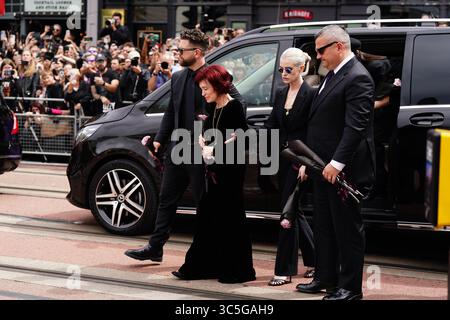 La famille d'Ozzy Osbourne (de gauche à droite) Jack Osbourne, Sharon Osbourne et Kelly Osbourne déposent des fleurs et regardent les messages et hommages floraux laissés sur le banc du pont Black Sabbath sur Broad Street à Birmingham en mémoire du chanteur Black Sabbath Ozzy Osbourne, alors que son corps est ramené dans sa ville natale pour une procession après sa mort la semaine dernière à l'âge de 76 ans. Date de la photo : mercredi 30 juillet 2025. Banque D'Images