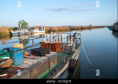 Bateau de pêche avec caisses et filets amarré dans un canal calme Banque D'Images