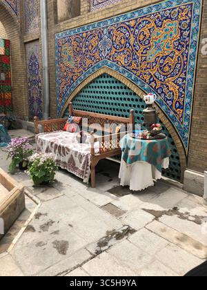 Un coin salon iranien traditionnel joliment décoré, avec des tielleries islamiques vibrantes, un banc en bois avec des textiles Paisley Banque D'Images