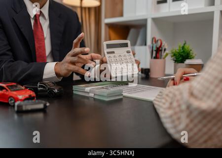 un vendeur de voitures explique les détails d'une voiture et le prix qui intéresse un acheteur, le directeur des ventes de la salle d'exposition a expliqué le montant de int Banque D'Images