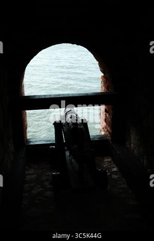 Canon historique à l'intérieur de la forteresse Golubac pointant vers le Danube, vu à travers une fenêtre voûtée en briques. Vue dégagée avec éclairage spectaculaire Banque D'Images