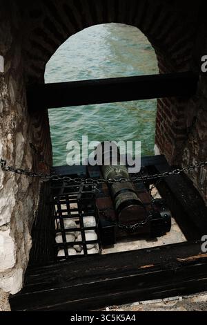 Canon historique à l'intérieur de la forteresse Golubac pointant vers le Danube, vu à travers une fenêtre voûtée en briques. Vue dégagée avec éclairage spectaculaire Banque D'Images