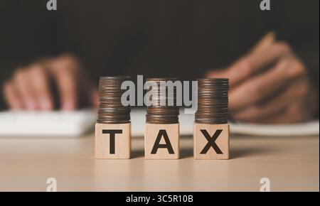 Concept de paiement d'impôt. Pièces empilées sur un bloc de cube en bois. Formulaire de déclaration de revenus des particuliers en ligne. Calcul de la déclaration fiscale. E-tax, gouvernement, STA Banque D'Images