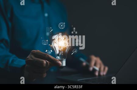 Homme d'affaires tenant l'ampoule avec des icônes d'affaires. Technologie d'application de connexion Internet mondiale d'entreprise et marketing numérique, financier, bancaire, lien Banque D'Images