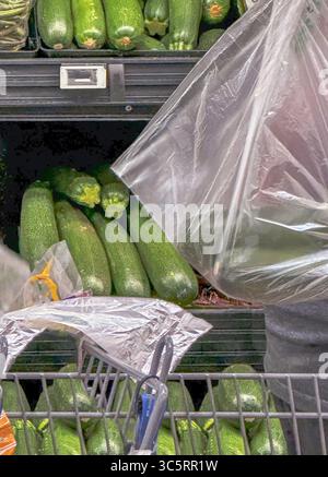 Les sacs en plastique sur le marché peuvent contenir des légumes, y compris beaucoup de courgettes vertes. Les étagères sont emballées et le chariot est nécessaire pour transporter les produits. Banque D'Images