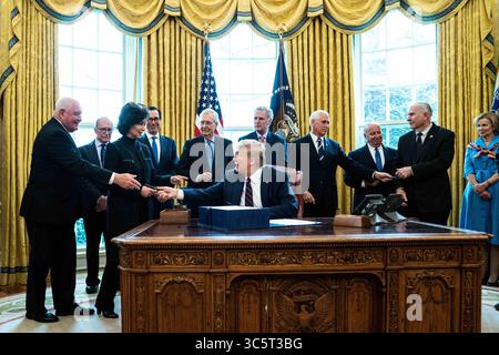27 mars 2020, Washington, District de Columbia, États-Unis : le président des États-Unis Donald J. Trump remet un stylo au secrétaire à l'Agriculture des États-Unis Sonny perdue, à gauche, après la cérémonie de signature du projet de loi de secours de deux billions de dollars contre le coronavirus dans le bureau ovale de la Maison Blanche à Washington, DC le 27 mars 2020. De gauche à droite derrière le président : le secrétaire perdue ; le directeur du Conseil économique national Larry Kudlow ; la secrétaire américaine aux transports Elaine Chao ; le secrétaire américain au Trésor Steven T. Mnuchin ; le chef de la majorité au Sénat américain Mitch McConnell (républicain du Kentucky) ; la maison américaine M Banque D'Images