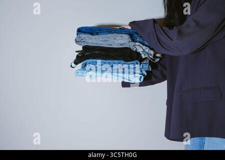 Femme tenant un Jean sur fond clair Banque D'Images