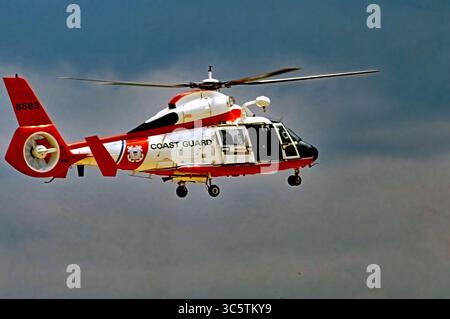 20 mai 1989, Camp Springs, Maryland, États-Unis : Camp Springs Maryland, États-Unis, 20 mai 1989.Un hélicoptère MH-65 Dauphin Short Range Recovery de la Garde côtière américaine passe en mode stationnaire tandis que le nageur de sauvetage à l'arrière se prépare à déployer le harnais de levage dans le cadre d'une démonstration des capacités de l'hélicoptère fabriqué par Airbus que la Garde côtière utilise pour diverses missions, y compris maintenant armé d'une version mitrailleuse (MH-65Cs) pour protéger le Capitole américain. (Crédit image : © Mark Reinstein/ZUMA Wire) Banque D'Images