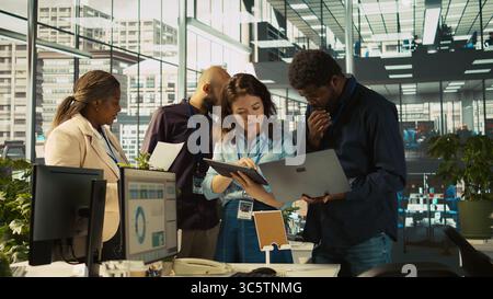 Collègues au bureau effectuant des séances de brainstorming, examinant les graphiques financiers, analysant les indicateurs de performance de l'entreprise. Collègues travaillant en équipe discutant, regardant les tendances des données, caméra B. Banque D'Images
