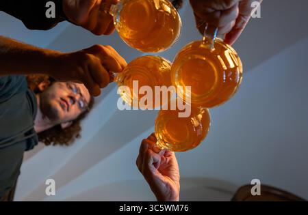 Prague, République tchèque, 5 août 2023. Photo en perspective cinématographique. Un groupe de quatre tasses vu d'en bas alors qu'ils se claquent ensemble dans un toast. Une vie Banque D'Images