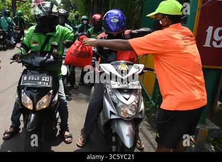 5 septembre 2019, Cipayung, Jakarta, Indonésie : des volontaires donnent des colis alimentaires aux chauffeurs de moto-taxi en ligne dans la région de Cipayung, Jakarta, le 18 avril 2020. Pas moins de 200 colis alimentaires ont été distribués en ligne aux chauffeurs de motos-taxis, car depuis que la co-pandémie a eu lieu en Indonésie, leurs revenus ont diminué. Depuis les nombreuses commandes précédentes pour le transport, les utilisateurs utilisent maintenant des chauffeurs pour commander de la nourriture, magasiner pour les nécessités quotidiennes ou livrer des marchandises. (Crédit image : © Dasril Roszandi/ZUMA Wire) Banque D'Images